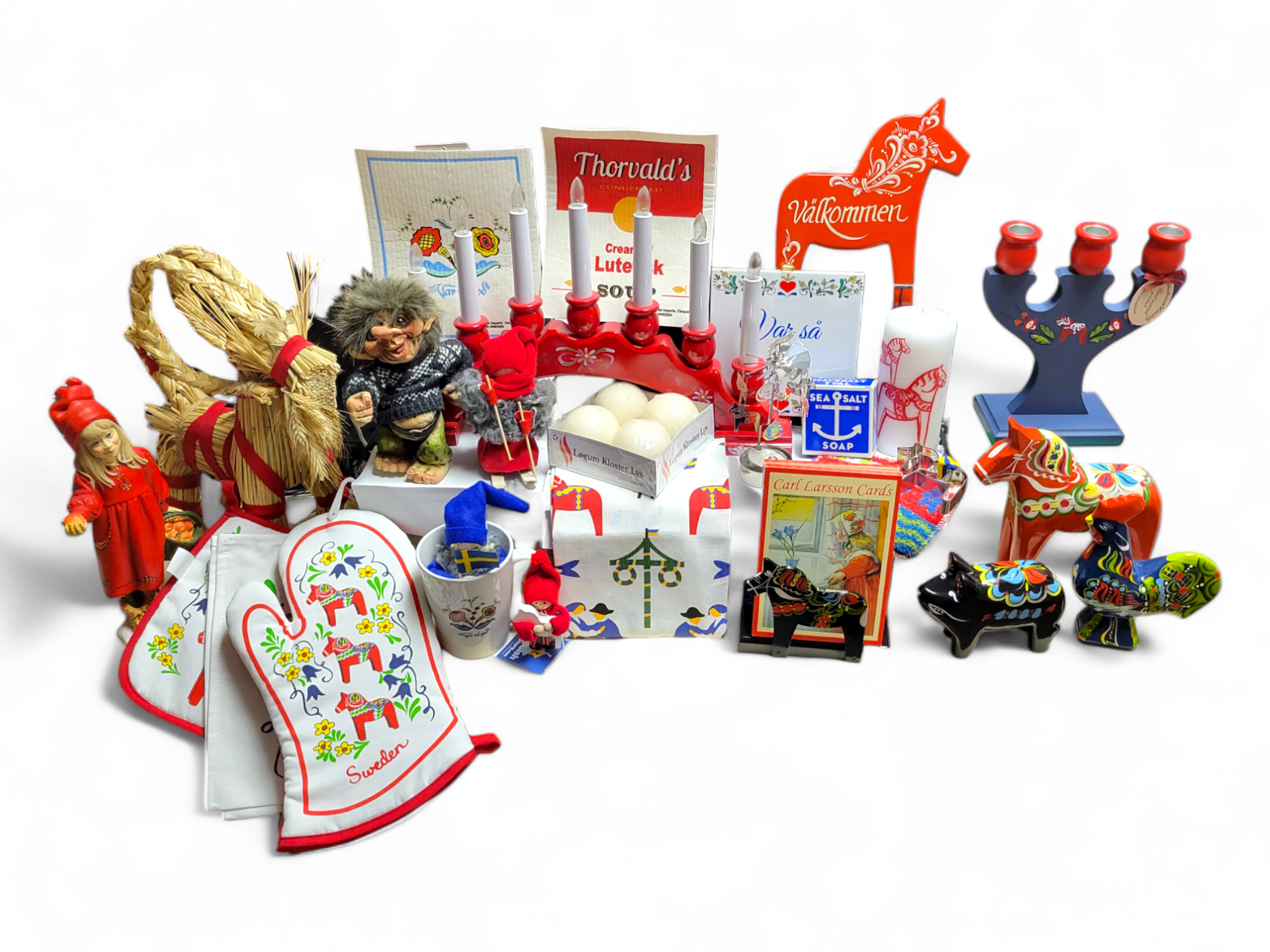 A collection of Swedish souvenirs, including Dala horses, a candelabra, oven mitts, a troll doll, figurines, cards, and decorative items, arranged on a white background.