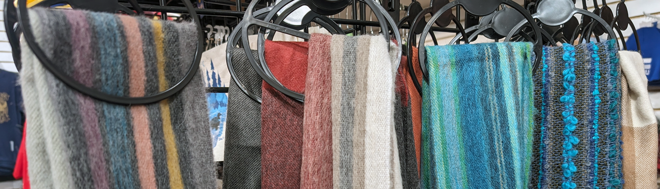 Colorful scarves with various patterns hanging on black circular displays.