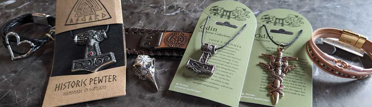 A selection of Viking-inspired jewelry including rings, necklaces depicting Thors hammer, and bracelets on a marbled surface.