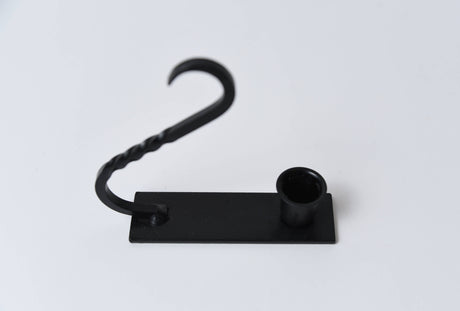 Iron taper holder with a flat base, cylindrical candle cup, and a curved, twisted handle.