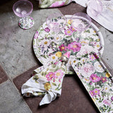A Koustrupco Denmark Rose Flower Garden round serving tray (14.9) is arranged with a rectangular plate, matching napkins, and three empty pink-tinted glasses on a stone tile floor.