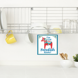 A dish rack with plates, bowls, cups, and glasses sits above a counter with utensils; a 6x6 Ive Got Swedish Roots! Swedish Dala Horse Wall Plaque decorates the wall, celebrating Swedish heritage.
