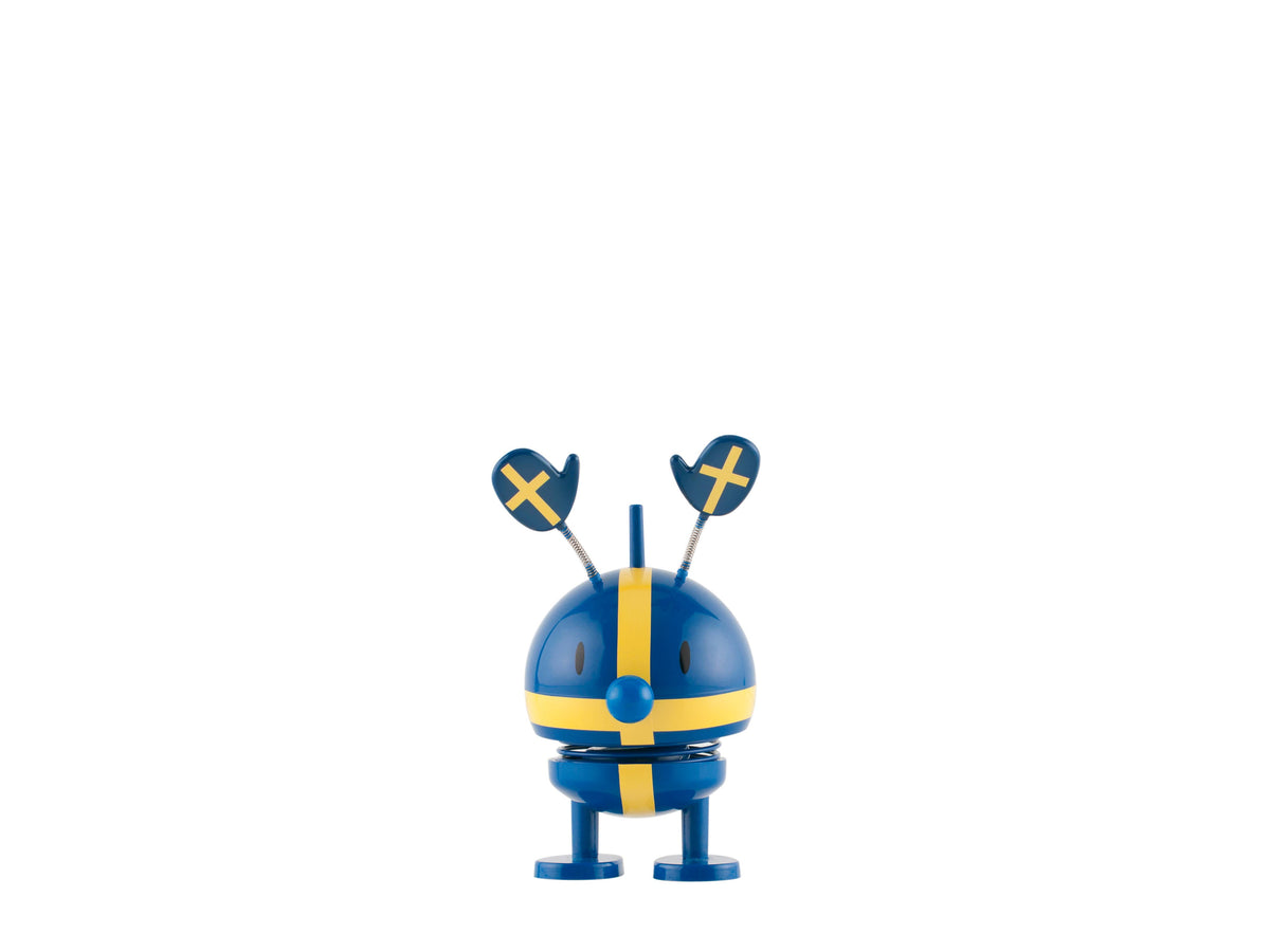 A blue and yellow desk toy with a rounded body, paddle-shaped antennas, and a visible cross pattern, shown against a white background.