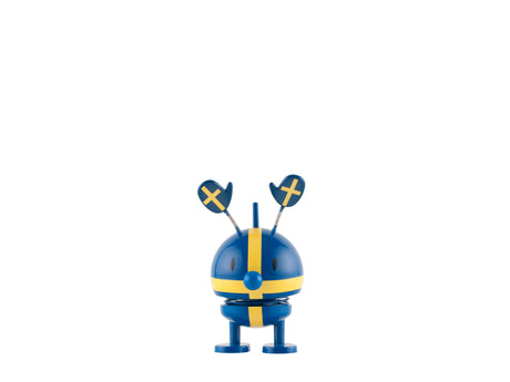 A blue and yellow desk toy with a rounded body, paddle-shaped antennas, and a visible cross pattern, shown against a white background.