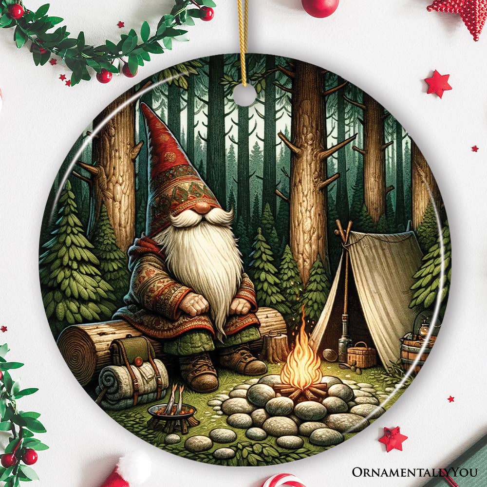 The Nordic Folk Gnome Forest Elder Themed Ceramic Ornament showcases a gnome with a tall hat, surrounded by a campfire, tent, and camping gear in a forest. Its ideal as a Christmas decoration or for adding Scandinavian decor to your home.