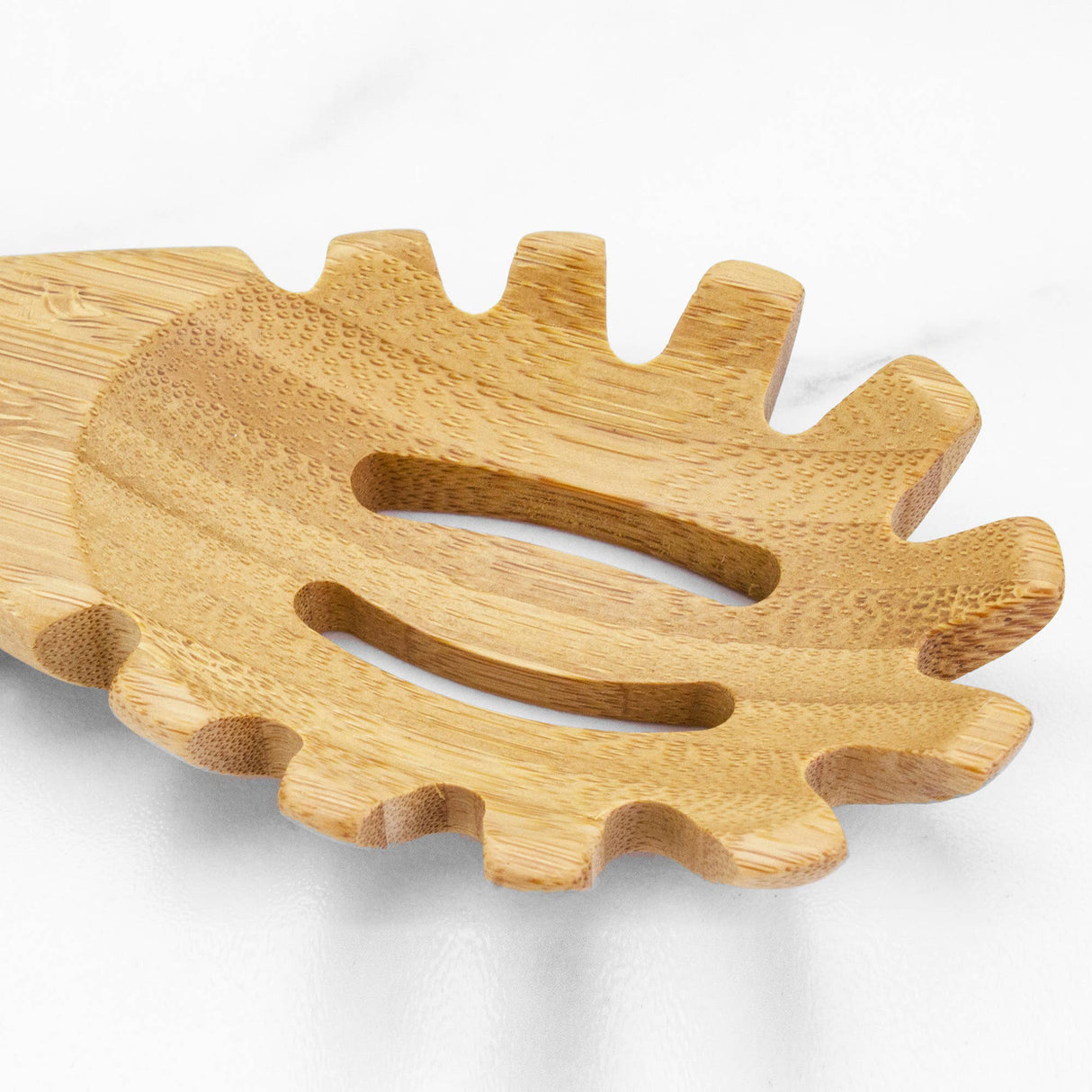 A close-up of the 14" Spaghetti Server Lambootensil, made from natural bamboo with fork-like prongs and drainage slots, is elegantly positioned on a white surface.