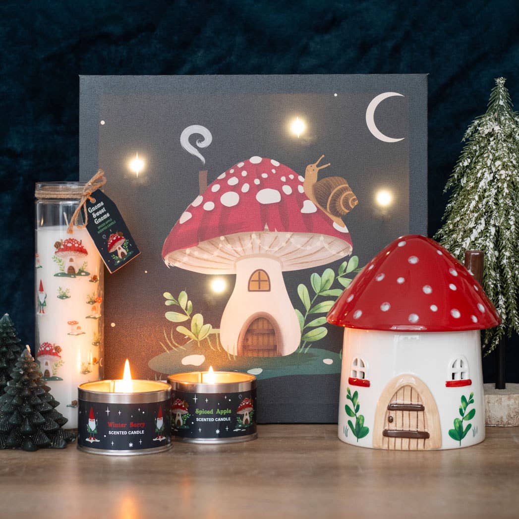 A cozy scene featuring a mushroom-themed painting and jar, highlighted by the "Gnome Sweet Gnome" candle display and small decorative trees. The winter forest design adds a charming touch to this inviting space.