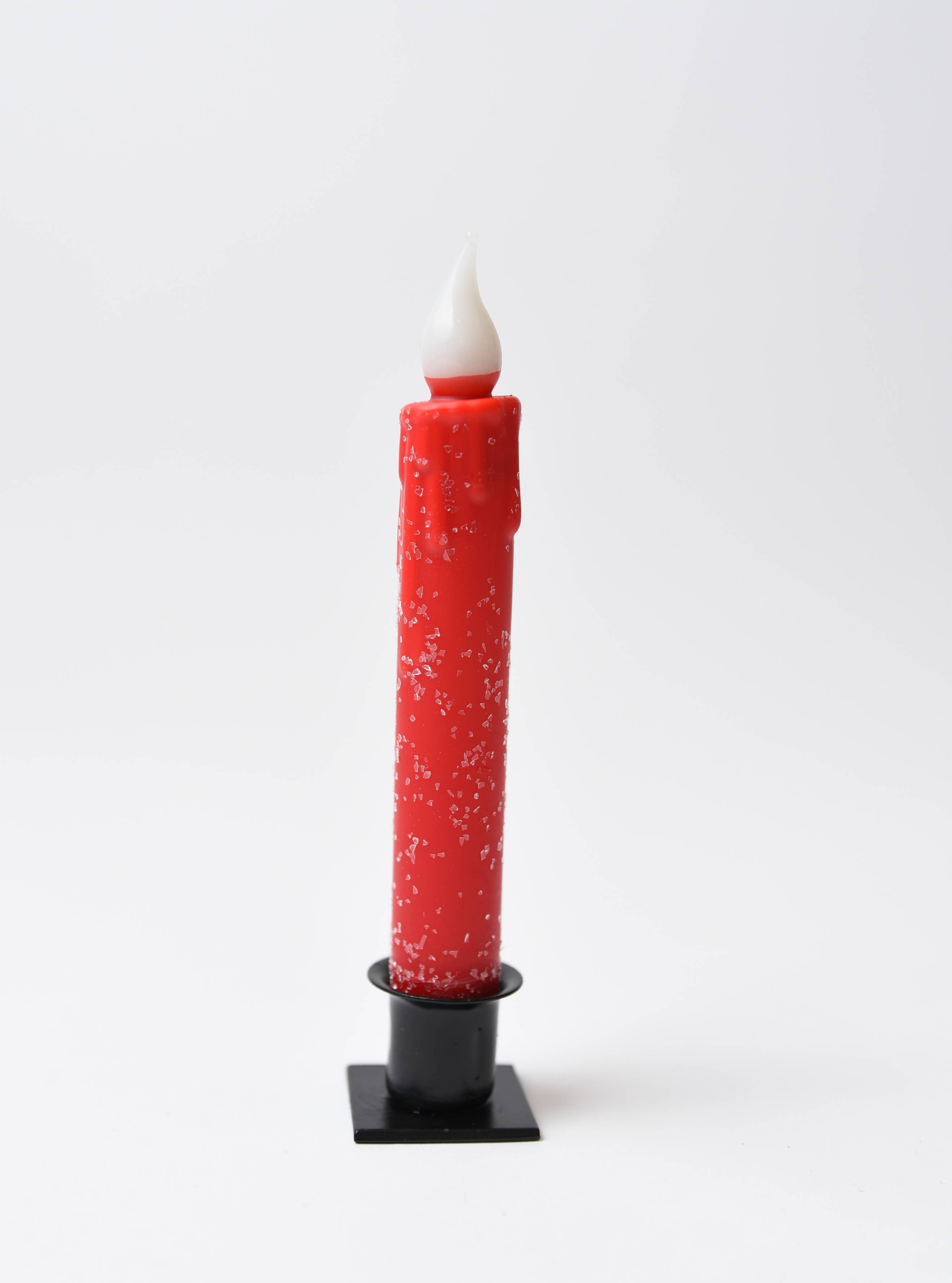 The Diamond Dusted Christmas LED Timer Taper Candle, featuring white specks, stands upright in a black holder against a plain white background.