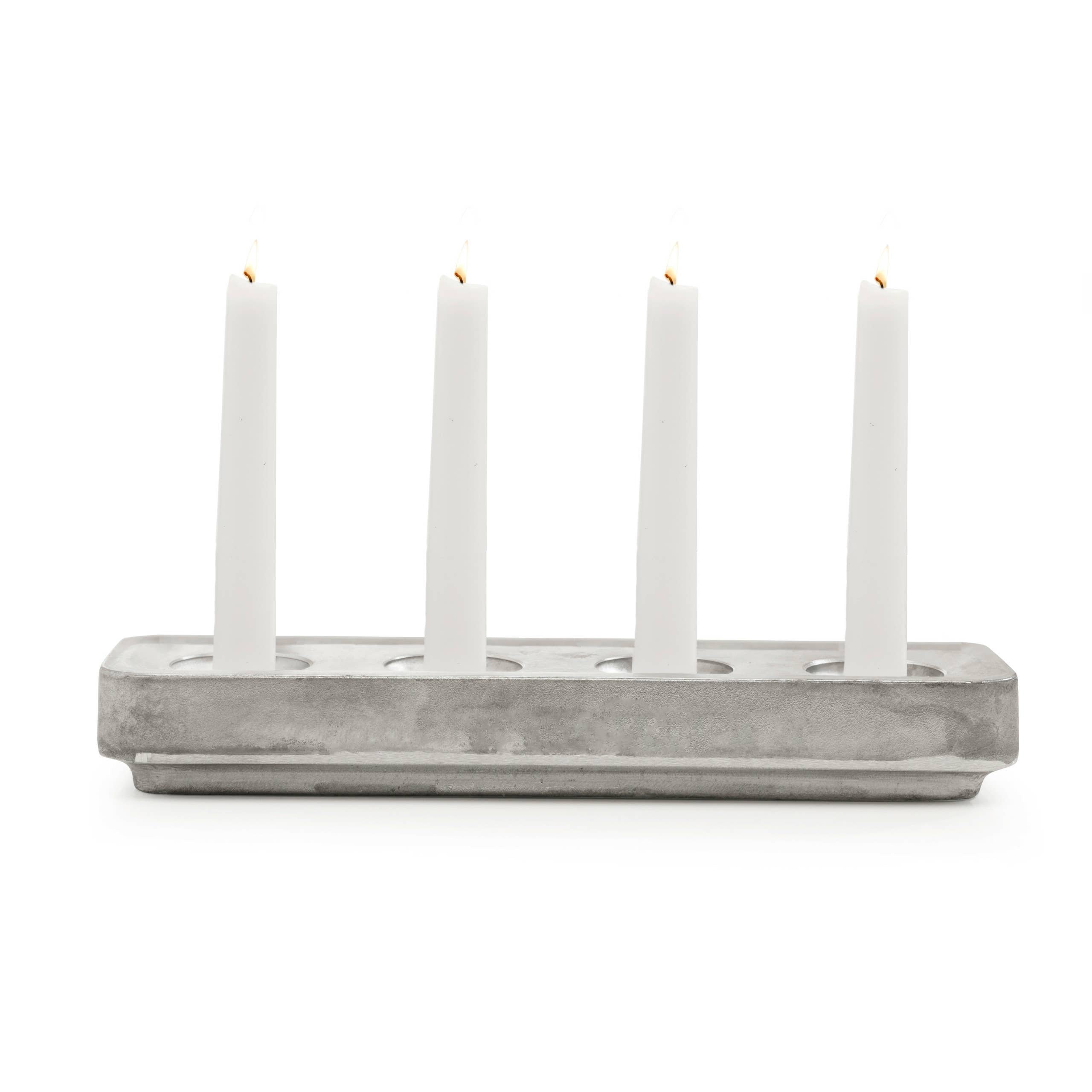 Four lit white candles sit gracefully in a Stumpastaken White Powdercoated Swedish Candle Holder made from recycled aluminum, set against a pristine white background.