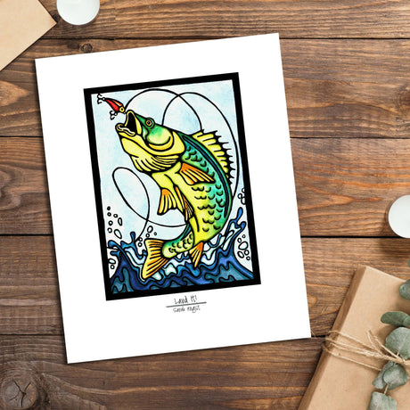 The Land It by Sarah Angst is an 11x14 giclee print with a white mat border, featuring a vibrant fish leaping for a lure—ideal lake life decor to brighten any space.