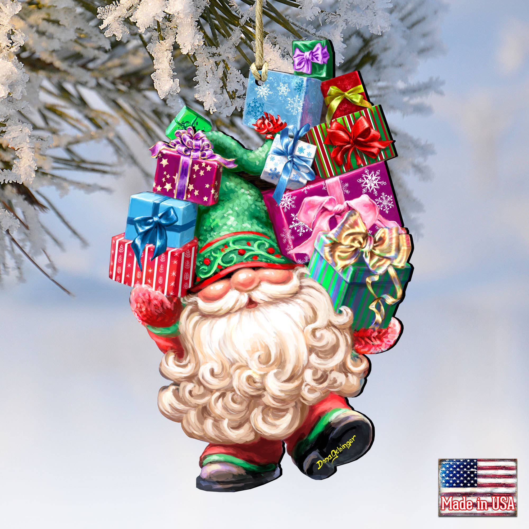 The Ornament: Gift Giver Gnome Handcrafted Ornament by D.Gelsinger features a charming gnome in a green hat holding a stack of colorful wrapped gifts, all hanging from a snow-covered pine branch.