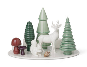 Porcelain advent candle holder on a circular white base, featuring a white deer, squirrel, three green stylized trees, two mushrooms, and an acorn.