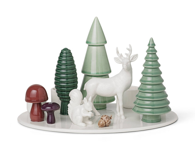 Porcelain advent candle holder on a circular white base, featuring a white deer, squirrel, three green stylized trees, two mushrooms, and an acorn.