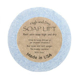 The blue Soap Lift, labeled High and Dry SOAP LIFT, is round with a brown label. Its eco-friendly, BPA-free bioplastic, made in the USA under the name Round A Bout Soap Lift Soap Saver.