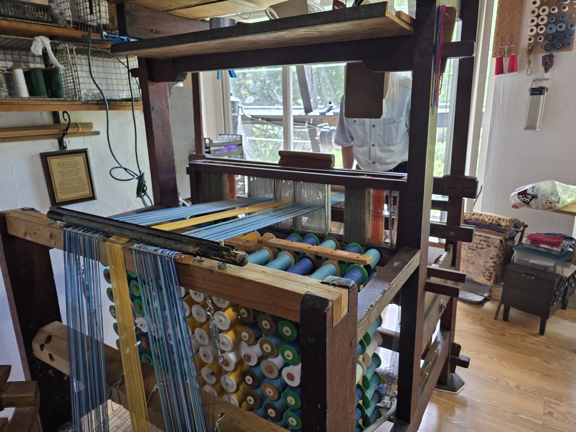 A vintage loom stands elegantly in a sunlit room, with its spools of 100% cotton thread reflecting the light, paired perfectly with the "Flag: Flag on Hanger - Sweden.