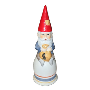The Bell: Tomte Sitting on a Bell Holding a Bag of Money is a 5.75 tall x 2 wide figurine featuring a gnome with a red hat and money bag, shown against a black background.