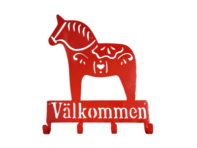 The Coat Hooks: Valkommen Dala Horse Sign is a red metal wall hook shaped like a Swedish Dala horse with "Välkommen" beneath—ideal as a unique entryway sign or for hanging coats.