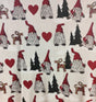 The Redlunds Noel Throw Blanket (130 x 170 cm) features a Scandinavian folk-inspired pattern with gnomes in red hats, red hearts, black fir trees, and yellow-red straw goats on a light background.
