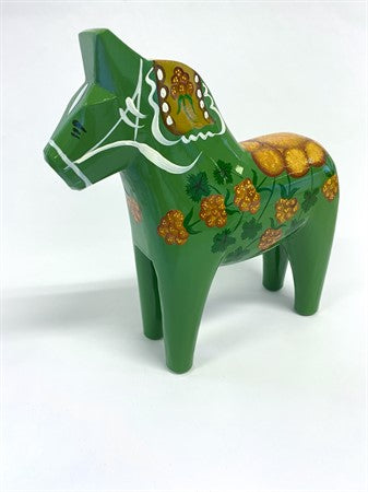 The Dala Horse: Salenhasten 13cm (5" tall) is a green hand-painted wooden figurine with yellow flowers and white patterns, reflecting Swedish craftsmanship, displayed on a white surface.