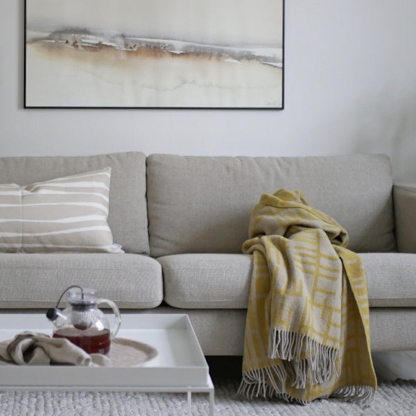 A light olive wool blanket draped over a couch.