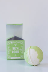 A green and white Soap: Coconut Island Bath Bomb sits before its matching green box labeled "Bath Bomb" against a plain white background.