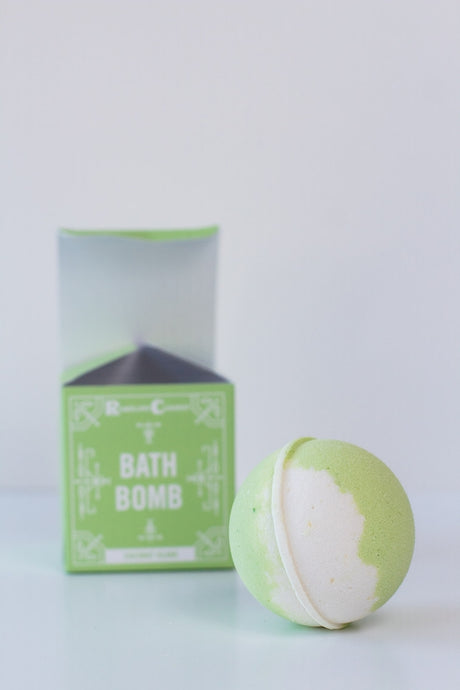 A green and white Soap: Coconut Island Bath Bomb sits before its matching green box labeled "Bath Bomb" against a plain white background.
