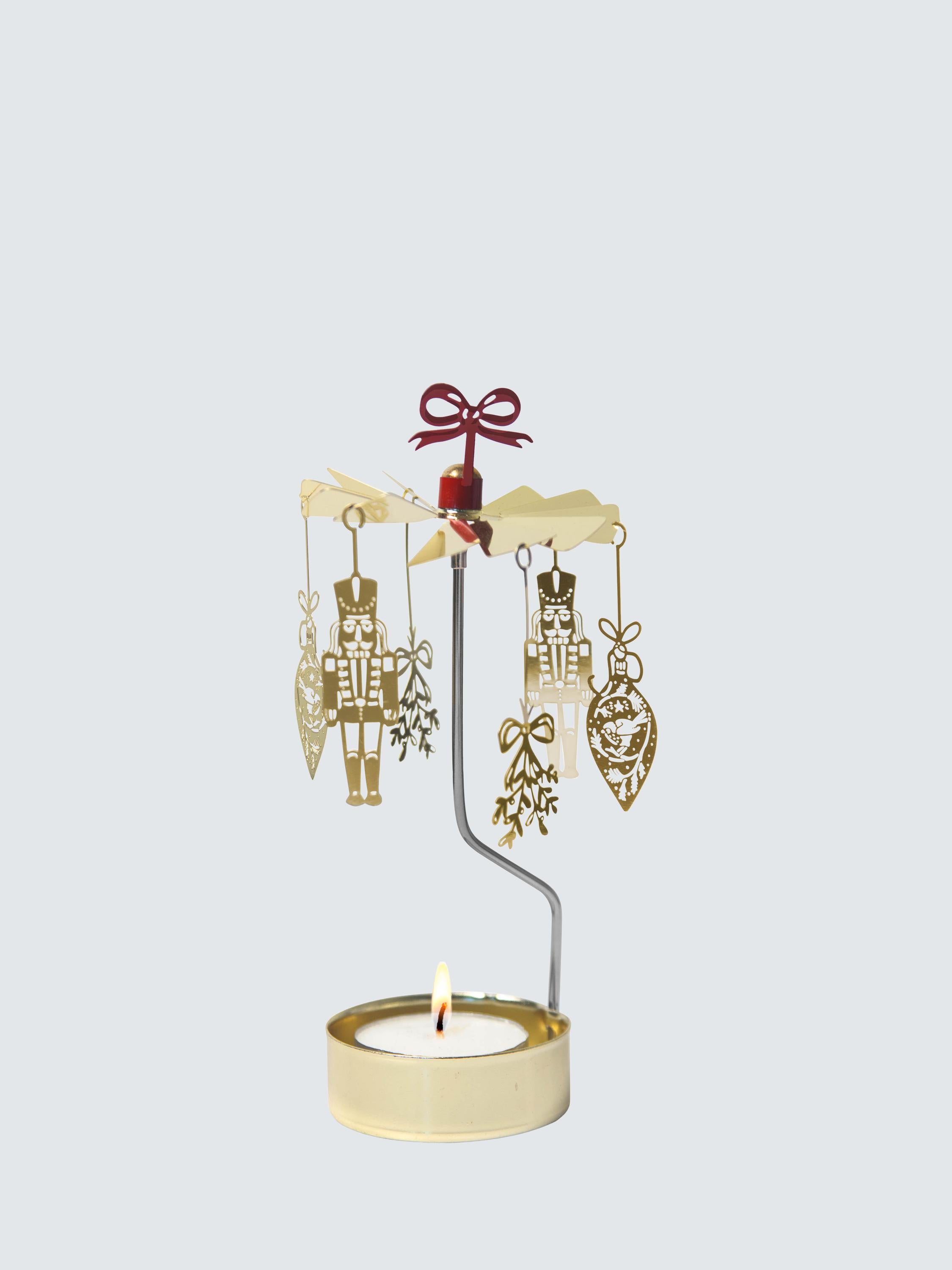 The Candle Holder: Nutcracker "Noel" Gold with Red Ribbon is a tea light rotary candle holder by Pluto Design Sweden, featuring nutcracker shapes and a festive red ribbon inspired by classic Swedish Christmas decor.