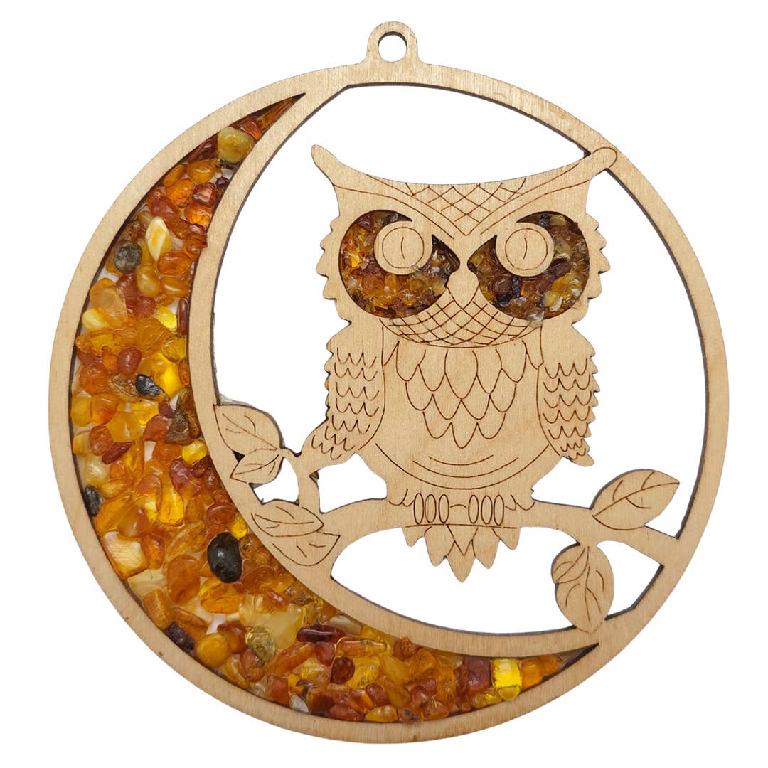 The Ornament: Owl Amber Suncatcher/Magnet showcases a captivating wooden owl with a Baltic Amber stone inlay, accentuating the crescent moon and leaf-adorned branch.