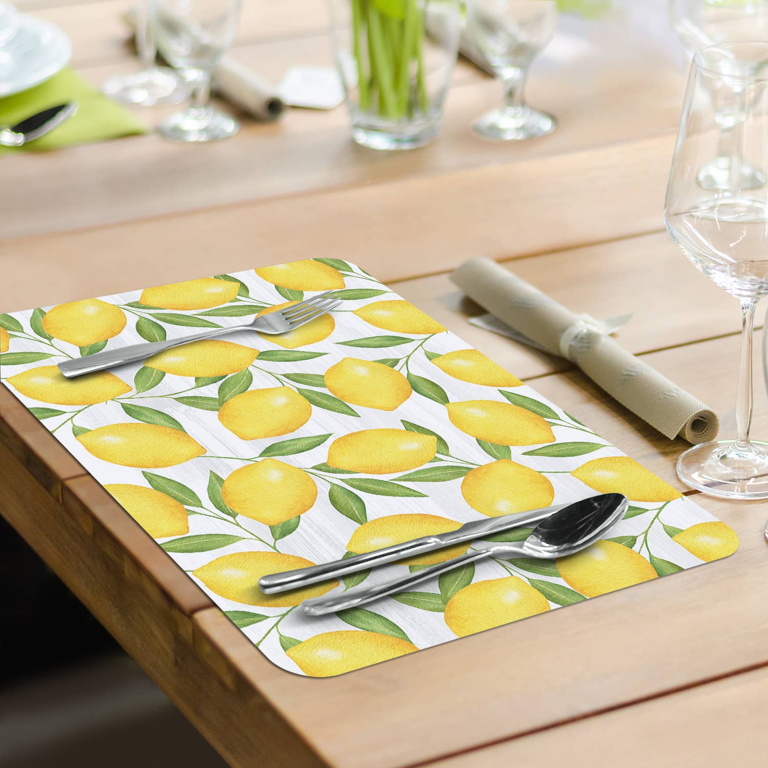 A delightful table arrangement showcases the Jardin De Citron Reversible Rectangular Plastic Placemat, making it an ideal housewarming gift. Paired with silverware, a rolled napkin, and empty glasses on a wooden surface, these easy-care placemats bring vibrant style to any setting.