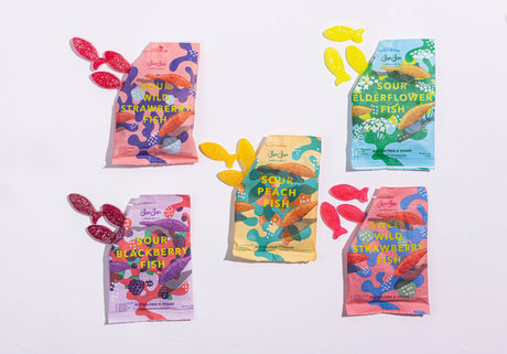 Five colorful packages of Bon Bon - Sour Wild Strawberry Fish vegan candy (150g) are displayed, each paired with matching gluten-free gummies, all arranged on a white background.