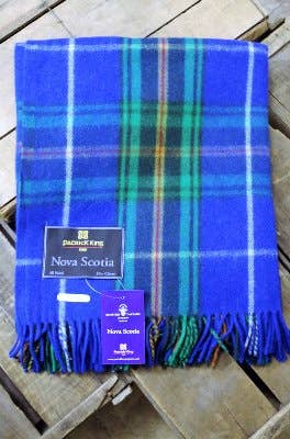 A folded blue, green, and yellow Nova Scotia Deluxe Highland Tartan Blanket—Merino Wool with fringe edges is displayed on wood, labeled Nova Scotia on two tags.