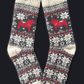 Swedish Passport Co's Socks: Red Dala Horse Black and Natural Wool Socks by Viking Knits feature a black, white, and red snowflake pattern with a Swedish Dala Horse on each sock, made from 70% wool. Displayed against a black background.