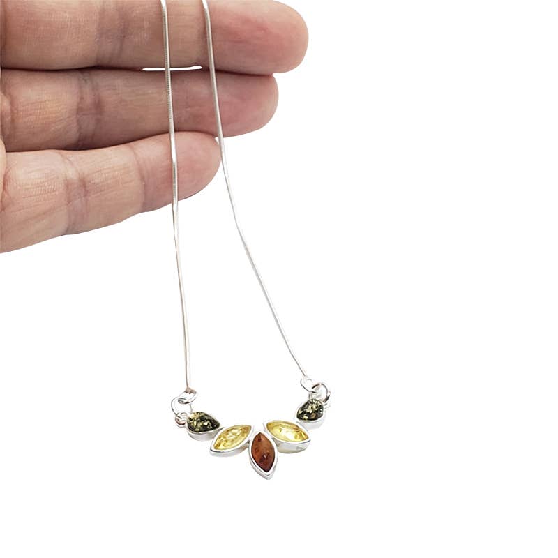 A hand holds a sterling silver necklace with a pendant featuring three marquise-shaped amber stones in orange, yellow, and green from the Marquise Teardrop Shaped Multi-Color 5 Amber Stones Sterling Silver Necklace collection.