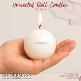 A hand holds a lit, peach ball candle (2.5" diameter) with a flat bottom; text specifies set of 4 decorative wax candles by Biedermann & Sons—Candles: Peach Ball Candles, 2.5" Diameter.