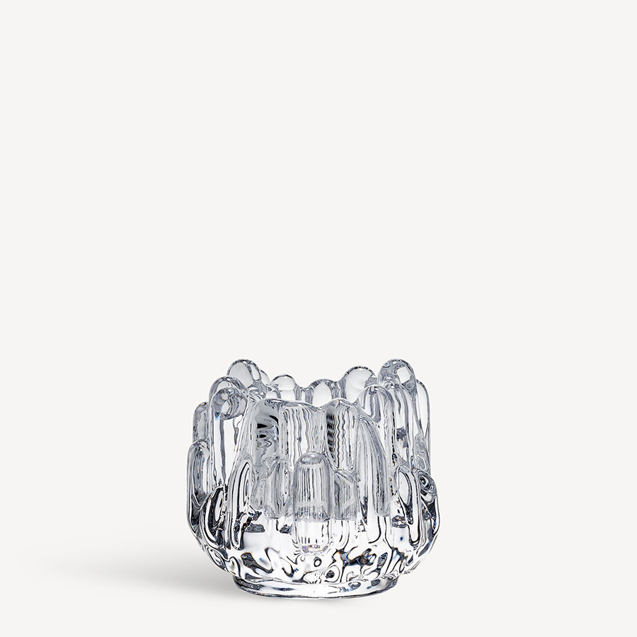 The KostaBoda Polar Votive Clear Small candle holder (H-86mm x D-95mm) features an irregular, textured glass surface, inspired by the Polar Votive collection and reminiscent of classic Kosta Boda glass sculptures.