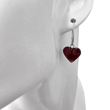 A close-up of a mannequin wearing Heart Cherry Amber Sterling Silver Earrings, featuring a dark red heart-shaped pendant.