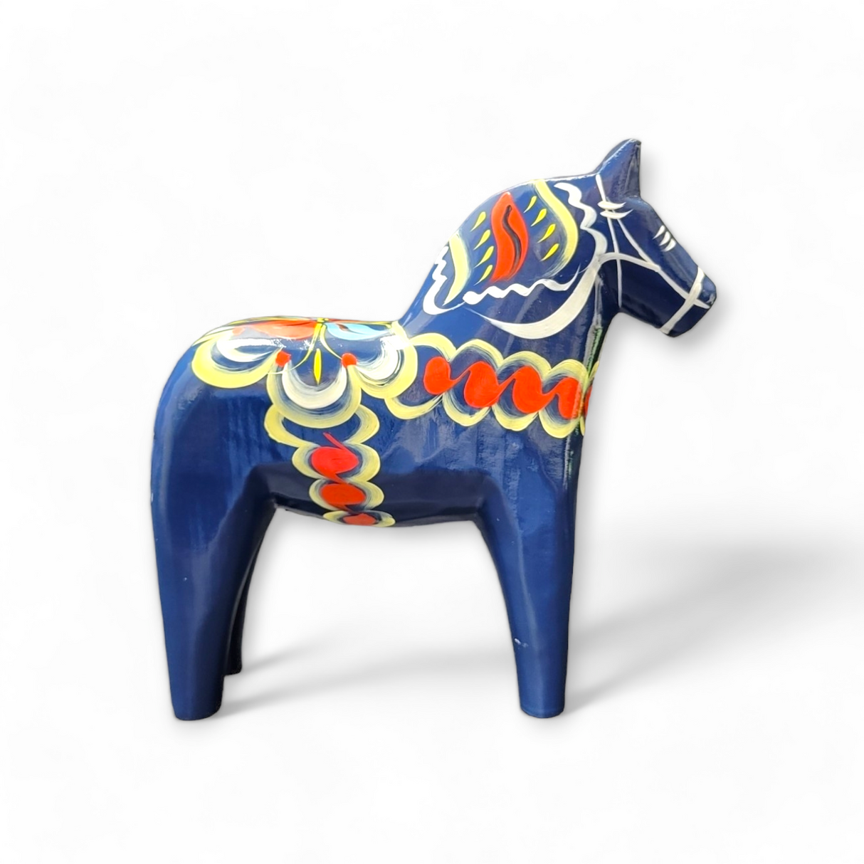 The Dala Horse: Blue, a hand-carved wooden figure, is elegantly adorned with vibrant kurbits patterns and stands gracefully on a white background.