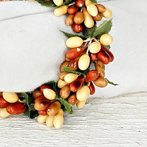 Napkin ring decorated with clusters of cream and reddish-brown pip berries and green leaves.