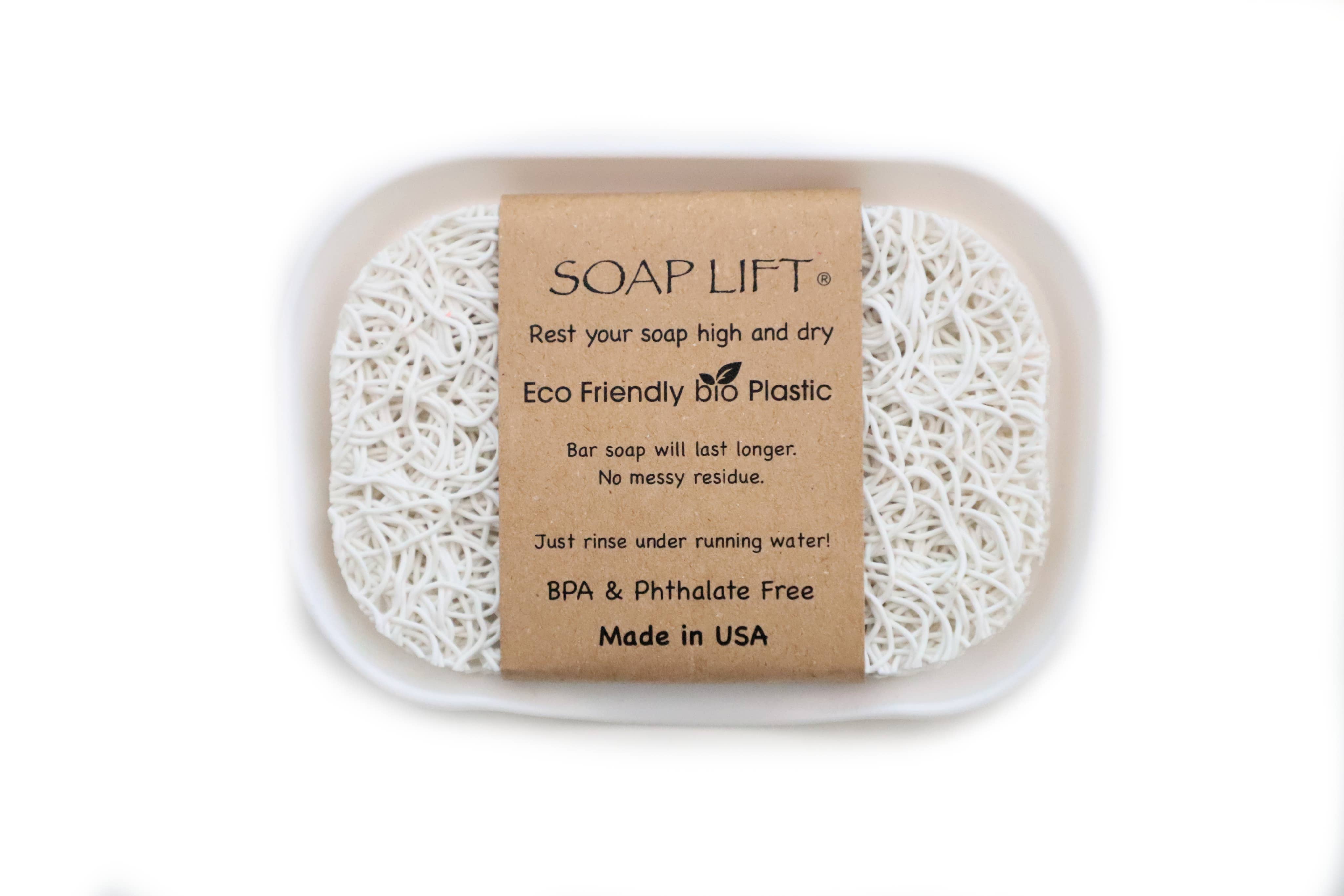 A white Soap Lift pad is snugly placed in a plastic tray, adorned with a brown label that emphasizes its eco-friendly benefits and its origin of being proudly made in the USA. It is part of the Soap Dish & Lift: Waterfall Soap Dish Set with Soap Lift Soap Saver - White.