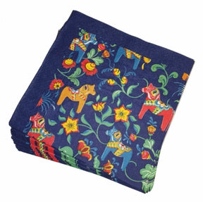 A vibrant stack of Leksand Blue Napkins showcases orange, red, and blue Swedish Dala Horses with kurbits on a rich dark blue background.