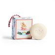 Round white bar soap with a teapot imprint next to a box featuring a bunny in a teacup illustration, tied with red and white striped string.