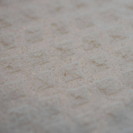 Close-up of a white textured surface with a repeating diamond pattern, similar to the design found on reusable dish towels.