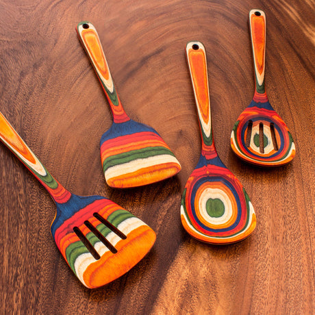 The Marrakesh Wooden Spatula - Birch, part of a set of four colorful birch kitchen utensils with striped patterns, is arranged on a wooden surface.