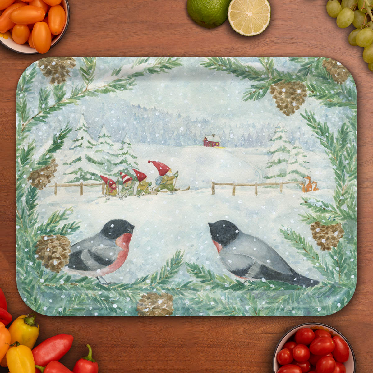 Placemat featuring bullfinches, pine branches with cones, skiing gnomes, a red house, a fox in snow, and assorted vegetables against a winter backdrop.