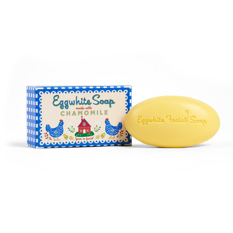 A yellow Eggwhite & Chamomile Facial Soap with “Eggwhite Facial Soap” embossed sits beside its blue and white gingham gift box, ideal for tightening pores and refreshing your skin.
