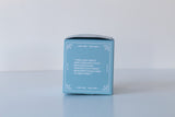 The Coastal Vibes Bath Bomb, handmade in Virginia Beach, comes in a light blue box featuring a white decorative border and a printed white quote on one side, displayed on a plain white surface.