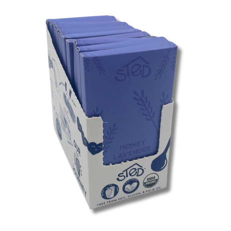 A box containing chocolate bars in purple wrappers labeled as honey lavender flavor, with visible icons indicating soy free, gluten free, and palm oil free.