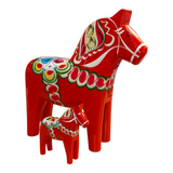 Two red Swedish Dala Horse figurines, handcrafted in Sweden and available in multiple sizes, feature colorful traditional Nordic folk art patterns, beautifully showcasing Sweden’s heritage.