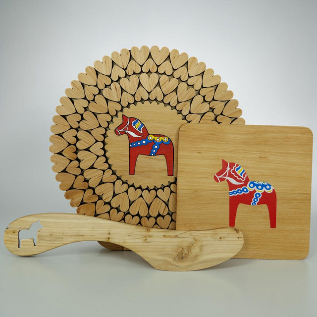 The Bundle: Dala Horse Kitchen Accessories includes three alder wood Scandinavian decor items—a heart-cutout trivet, a square cutting board, and a spatula with a Dala Horse cutout—perfect for charming kitchen style.