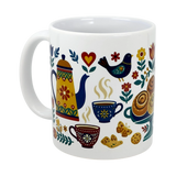 The Swedish Gift Store’s 11 oz "Mug: Swedish Fika Traditions Wraparound Ceramic Mug" features colorful folk art of a teapot, cups, bird, heart, flowers, cinnamon rolls, and cookies on white ceramic.